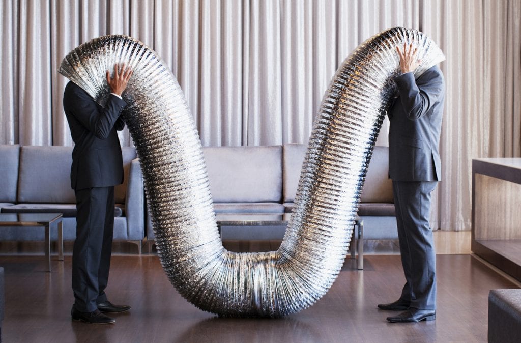 Businessmen with their heads inside metal tubing
